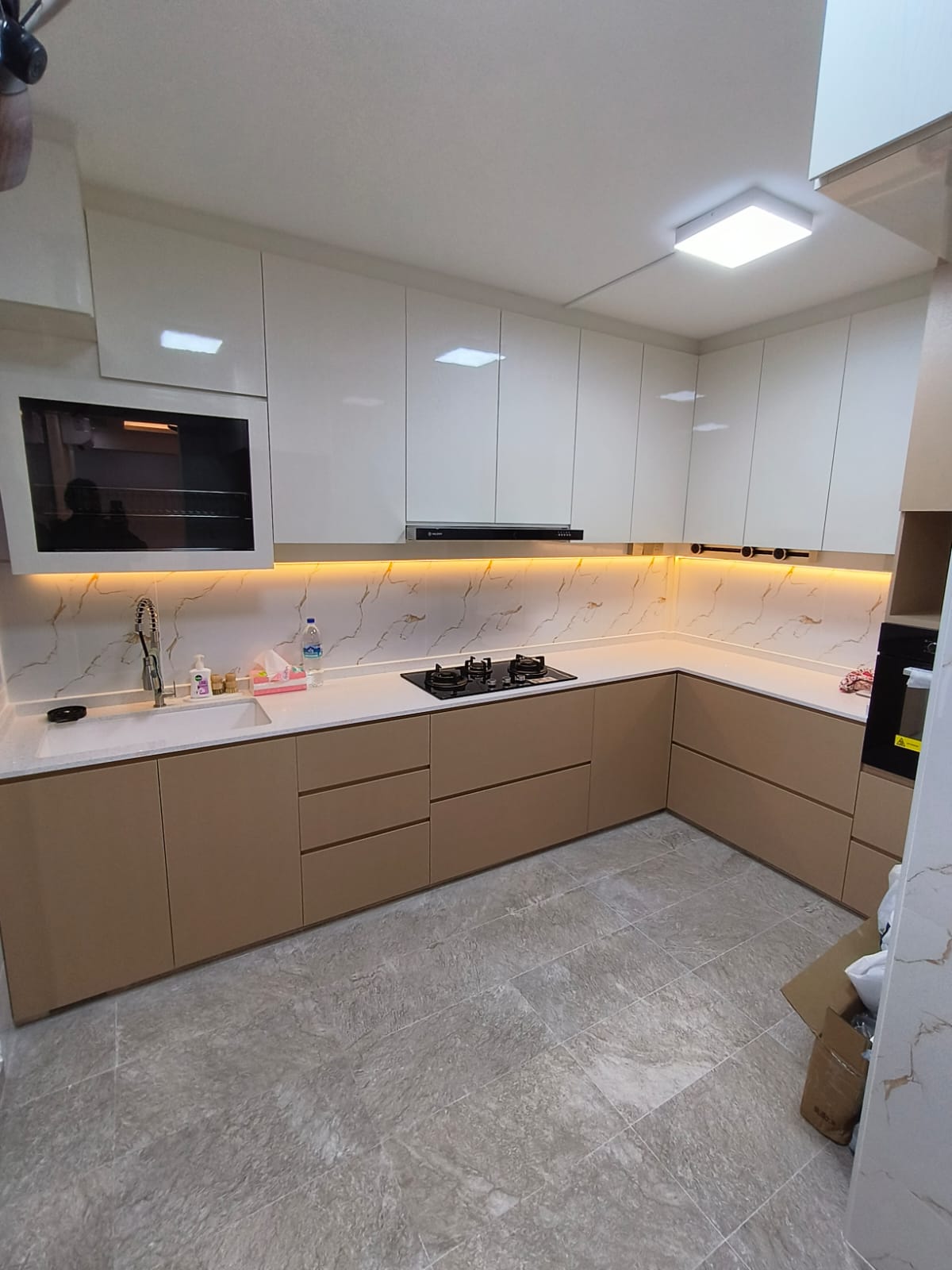 Modern kitchen with white cabinets, marble countertop, and tiled floor.
